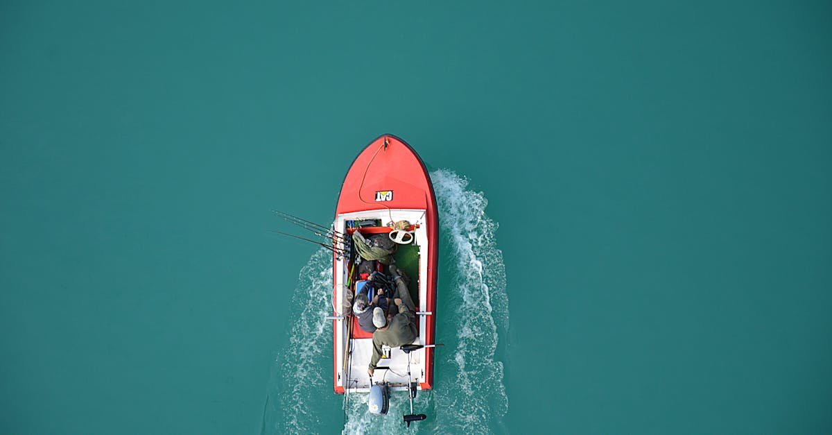 Top view of a red motorboat with fishermen navigating open turquoise waters.